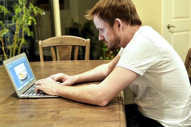bearded man typing on laptop