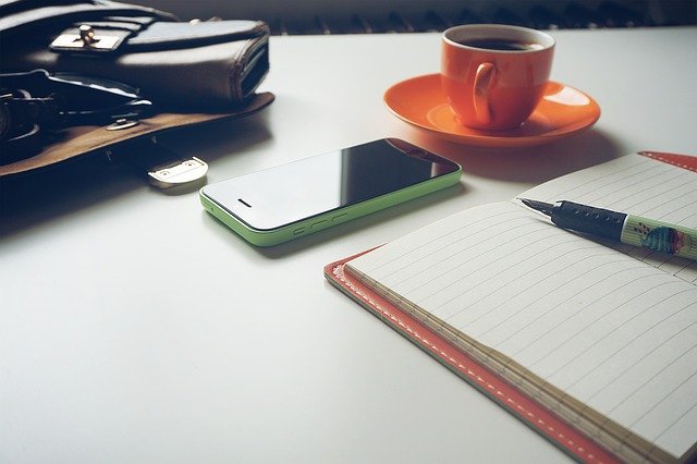 table with notepad, coffee, smartphone and wallet